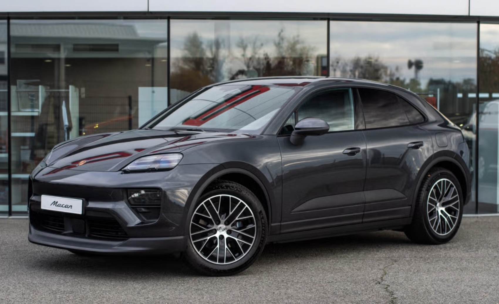 Porsche Macan gris exposé devant la vitrine d'une concession automobile
